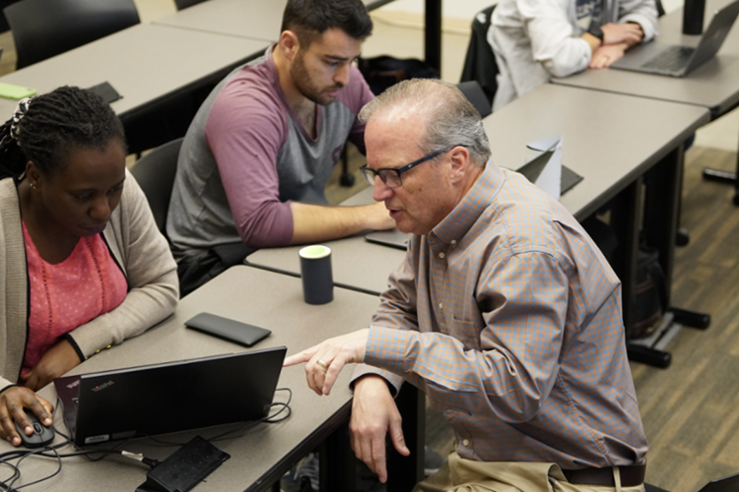 Dr. Strong with a student on their laptop